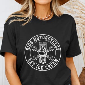 May include: Black t-shirt with a white graphic. The graphic is a circular design with the words "Ride Motorcycles Eat Ice Cream" surrounding an ice cream cone, piston, and wrenches.