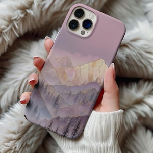May include: A lavender phone case featuring a mountain landscape design. The case has a matte finish and a detailed illustration of mountains, trees, and a sky gradient. Gold accents highlight the mountain ridges.