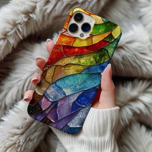 Może przedstawiać: Kolorowe etui na telefon z witrażowym wzorem. Etui posiada żywą mozaikę tęczowych kolorów, w tym czerwony, pomarańczowy, żółty, zielony, niebieski i fioletowy. Projekt ma teksturowany wygląd z błyszczącym wykończeniem.