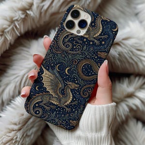 Könnte beinhalten: Eine Handyhülle mit einem detaillierten Drachendesign in Gold und Grün auf dunkelblauem Hintergrund. Das Muster wiederholt Drachen, Sterne und Halbmonde. Die Hülle wird in einer Hand gehalten.