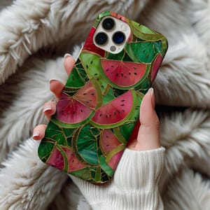 May include: A phone case featuring a watermelon design. The case has a green and red color scheme with gold accents. The design includes watermelon slices and green leaves. The case is held in a person's hand.