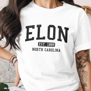 White t-shirt with "ELON EST. 1889 NORTH CAROLINA" in black block letters.