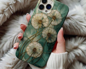 Op de afbeelding: Een teal telefoonhoesje met een paardenbloemontwerp. De hoes heeft een groene marmerachtige achtergrond met goudkleurige stelen. De paardenbloemen zijn wit met gedetailleerde zaadkoppen. De telefoonhoes wordt vastgehouden door een persoon die een witte trui draagt.