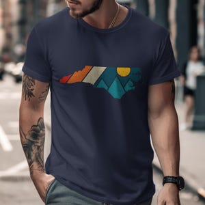Navy t-shirt with North Carolina map design featuring mountains and sun.