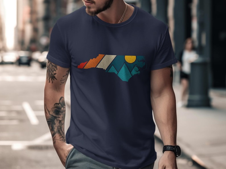 Navy t-shirt with North Carolina map design featuring mountains and sun.