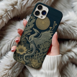May include: A dark blue phone case with a gold dragon illustration set amongst floral and botanical elements. The design includes a golden sun and intricate foliage, creating a fantasy theme. The case is held in a person's hand.