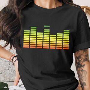 May include: Black t-shirt featuring a colorful graphic equalizer design. The equalizer bars transition from green to yellow to orange, creating a vibrant visual effect. The design is centered on the shirt, offering a bold statement.