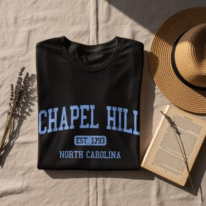 Black t-shirt with "Chapel Hill EST. 1793 North Carolina" in blue text.