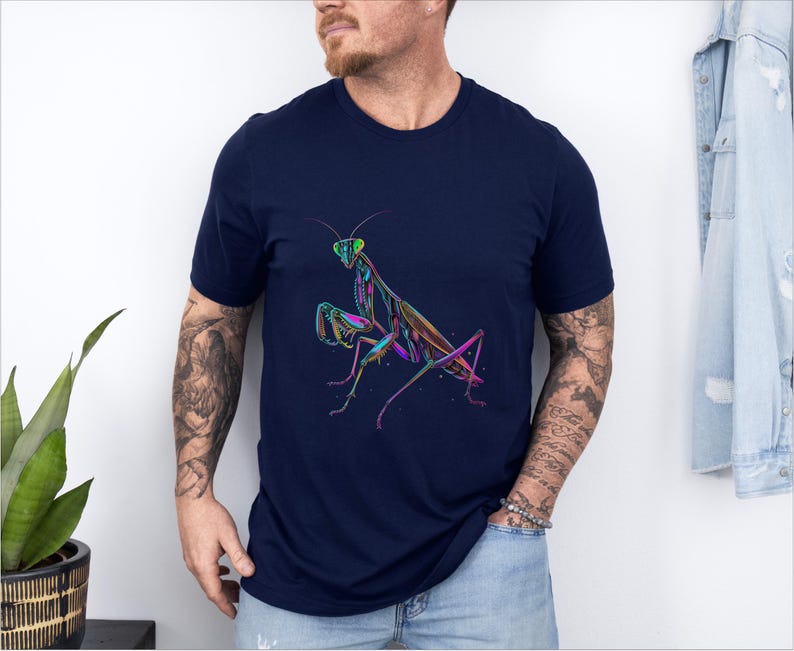 May include: A navy blue t-shirt with a colorful graphic of a praying mantis. The mantis is outlined in black and filled with shades of green, pink, and blue.