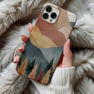 May include: A phone case featuring a landscape design with mountains and trees. The case has a color palette of muted earth tones, including brown, beige, and green. The design is an abstract representation of a forest and mountain range.
