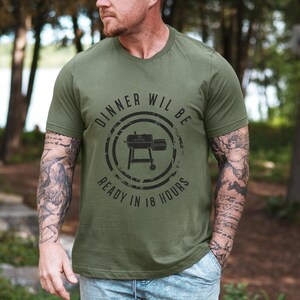 K&ouml;nnte beinhalten: Ein gr&uuml;nes T-Shirt mit einer schwarz-wei&szlig;en Grafik eines Smokers. Der Text auf dem Shirt lautet "Dinner will be ready in 18 hours".