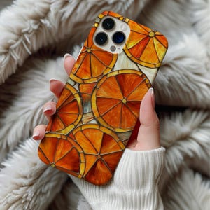 May include: A smartphone case featuring a vibrant stained glass mosaic pattern of sliced oranges in shades of bright orange, deep amber, and yellow. The design consists of multiple circular fruit segments outlined in dark lines, covering the entire back.