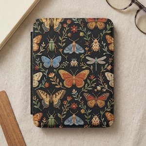 May include: A rectangular e-reader case featuring a black background with a repeating pattern of colorful embroidered-style insects including butterflies, moths, dragonflies, and beetles, interspersed with small floral vines and green leaves.