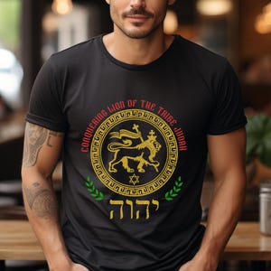 May include: Black t-shirt featuring a gold and yellow emblem with a lion, cross, and Star of David. The text "CONQUERING LION OF THE TRIBE JUDAH" arches around the emblem in red. Green laurel branches flank the bottom.