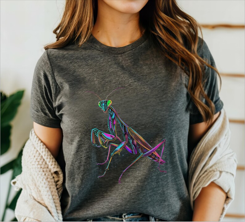 May include: A dark grey t-shirt with a colorful graphic of a praying mantis. The mantis is outlined in black and filled with vibrant colors, including green, blue, pink, and purple.