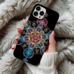 May include: Black smartphone case featuring a colorful geometric design with blue, pink, and gold accents. The case has a glossy finish and a camera cutout. The design is a symmetrical pattern of circles and lines.