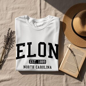 White t-shirt with "ELON EST. 1889 NORTH CAROLINA" text.