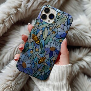 May include: A blue and green phone case featuring a stained glass design with bees and flowers. The case has a floral pattern with gold accents. The case is made of a hard, durable material.