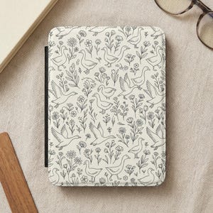 May include: A cream-colored e-reader cover featuring a repeating pattern of line-drawn geese and floral elements. The design includes various poses of geese among flowers and foliage, creating a whimsical, nature-inspired aesthetic.
