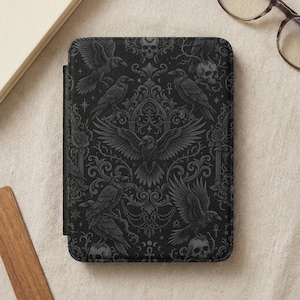 May include: Black e-reader cover featuring a gothic design with ravens, skulls, and ornate scrollwork. The cover has a dark, textured background and a magnetic closure. The overall theme is dark and mysterious.