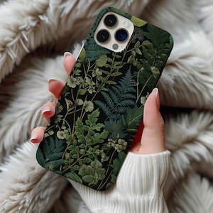 May include: A phone case featuring a botanical design with various shades of green leaves and plants against a black background. The case has a glossy finish and a camera cutout.