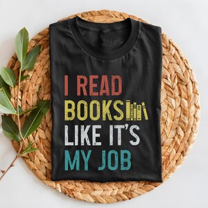 May include: Black t-shirt with a vintage-style graphic that reads "I read books like it's my job". The graphic features a stack of books with a rainbow colour scheme.