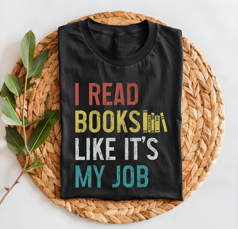 May include: Black t-shirt with a vintage-style graphic that reads "I read books like it's my job". The graphic features a stack of books with a rainbow colour scheme.