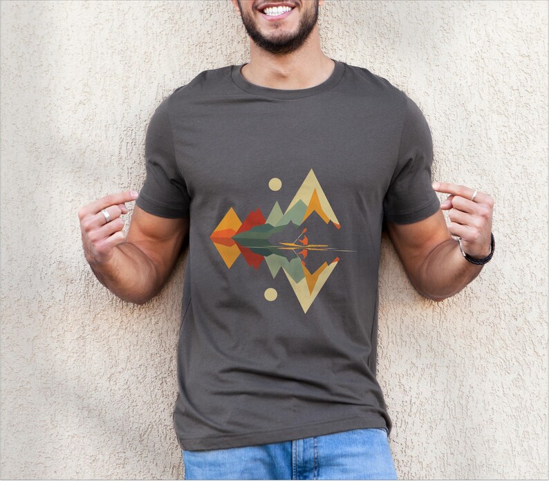 May include: A dark gray t-shirt with a geometric design of mountains and a lake reflecting the mountains. The design is in shades of orange, yellow, green, and blue.