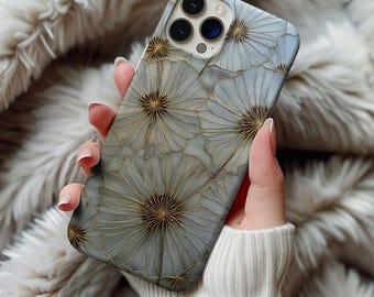 May include: A phone case featuring a floral design with a light blue and gold color scheme. The case has a repeating pattern of stylized flowers with gold outlines and a textured appearance. The phone case is held in a person's hand.
