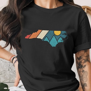 Black t-shirt with North Carolina outline featuring mountains and a sunset.