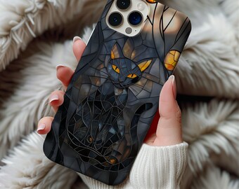 Puede incluir: Funda de teléfono negra con un gato negro con diseño de vidriera. El gato tiene ojos y orejas amarillas, sobre un fondo oscuro con un árbol y una luna. La funda está en la mano de una persona.