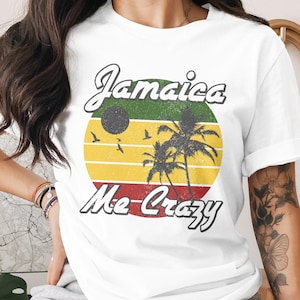 May include: White t-shirt with a retro design featuring the text "Jamaica Me Crazy." The design includes a circular graphic with the colors of the Jamaican flag, palm trees, birds, and a sun.