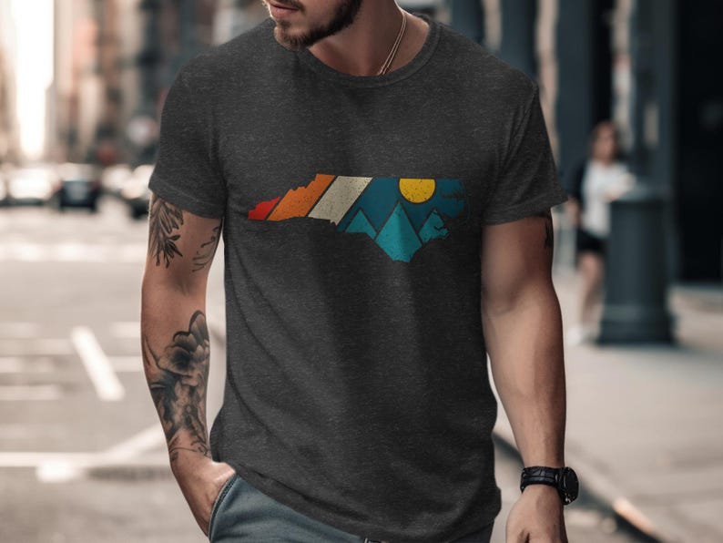 Dark t-shirt with North Carolina outline featuring mountain and sunset graphic.