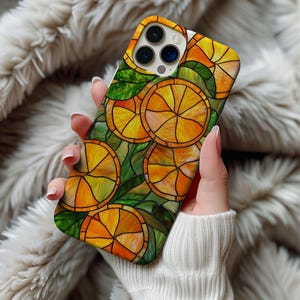 May include: A phone case with a stained-glass effect, depicting orange slices and green leaves. The case has a glossy finish and a vibrant colour scheme of orange, yellow, and green. The design evokes a citrus fruit theme.