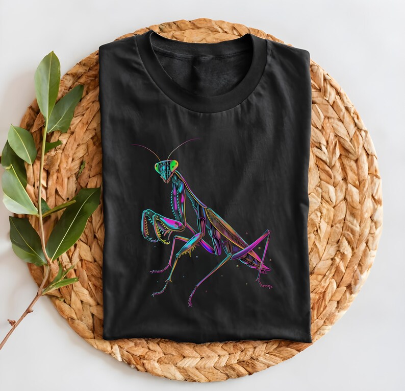 May include: Black t-shirt with a colorful graphic of a praying mantis. The mantis is outlined in black and filled with shades of pink, purple, green, and blue.