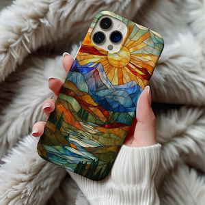 Puede incluir: Una funda para teléfono de estilo vitral con una escena de montaña colorida y un sol amarillo brillante. La funda está diseñada para un iPhone.