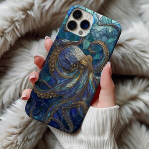 May include: A smartphone case featuring a stained-glass style octopus design. The case showcases a detailed illustration of an octopus in shades of blue and gold, with a mosaic-like background. The case is held in a person's hand.