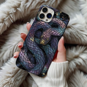 May include: A smartphone case with a detailed illustration of a snake in shades of purple, blue, and gold. The snake's scales are intricately designed, and the case has a glossy finish. The case is held in a person's hand.