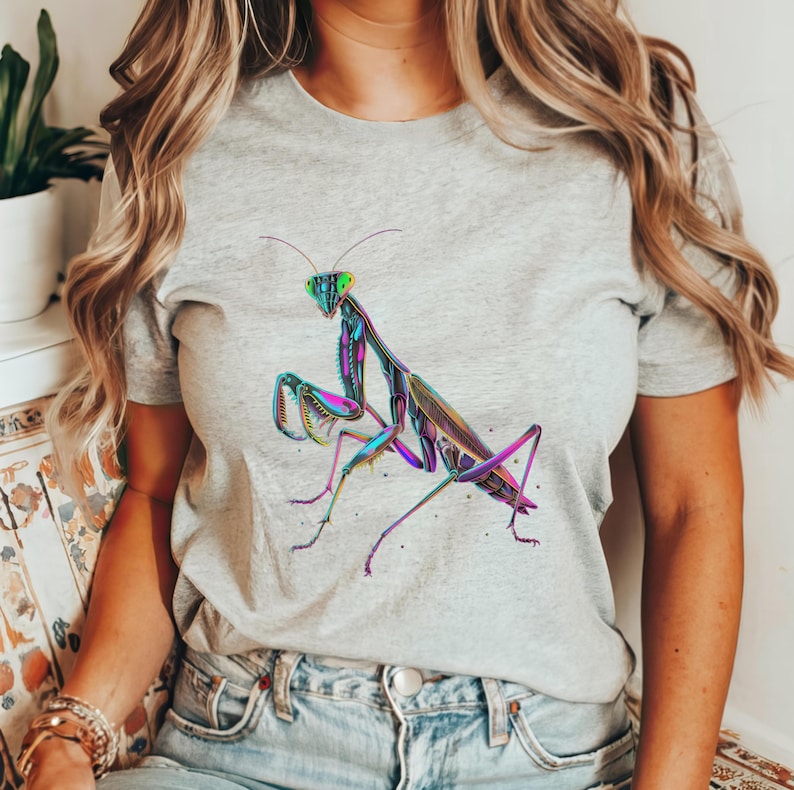 May include: A gray t-shirt with a colorful graphic of a praying mantis. The mantis is iridescent with shades of green, blue, and purple.