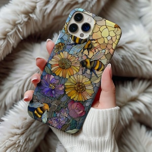 May include: A colorful phone case featuring a stained-glass design with bees and flowers. The case showcases yellow sunflowers, purple and pink flowers, and several bees with black and yellow stripes. The background has a mosaic pattern.
