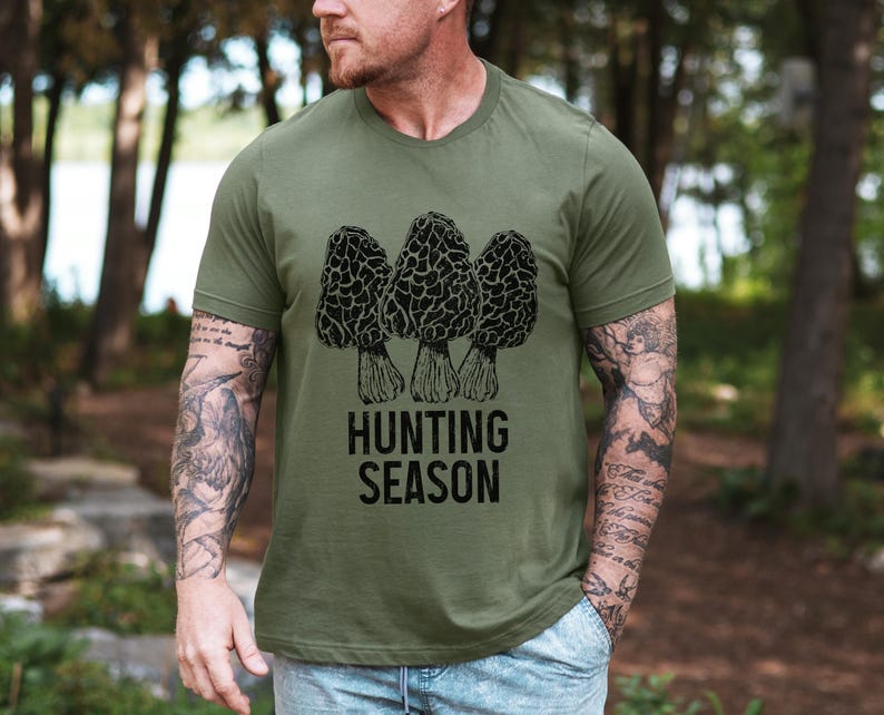 May include: A green t-shirt with a black and white illustration of three morel mushrooms and the text "Hunting Season".