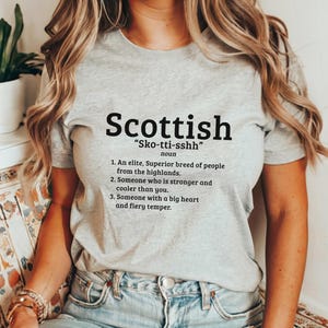 May include: A gray t-shirt with a black graphic that says "Scottish" and defines the word as "Sko-tti-sshh" with a humorous definition of the word.