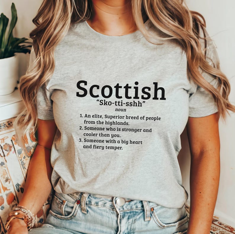 May include: A gray t-shirt with a black graphic that says "Scottish" and defines the word as "Sko-tti-sshh" with a humorous definition of the word.