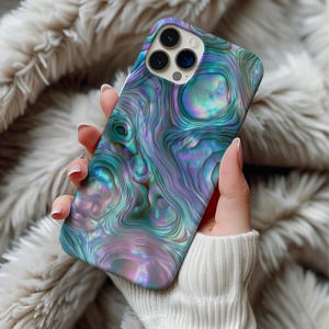 May include: A smartphone case featuring a vibrant, iridescent abalone shell pattern with swirling shades of teal, purple, and blue. The design mimics the natural, glossy texture of mother-of-pearl, complete with a cutout for a triple-lens camera system.
