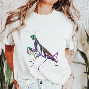 May include: White t-shirt with a colorful graphic of a praying mantis on the front.