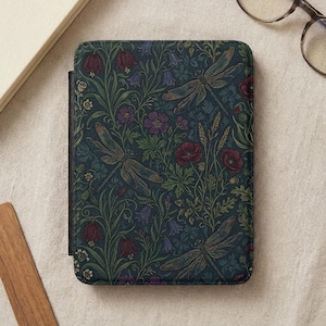 Puede incluir: Funda de lector electrónico de color verde azulado oscuro con un estampado floral y de libélulas. El diseño incluye amapolas rojas, flores moradas y follaje verde. La funda tiene un lomo negro y un cierre magnético.