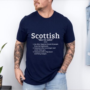 May include: A navy blue t-shirt with white text that reads "Scottish "Sko-tti-sshh" noun 1. An elite, Superior breed of people from the highlands. 2. Someone who is stronger and cooler than you. 3. Someone with a big heart and fiery temper."