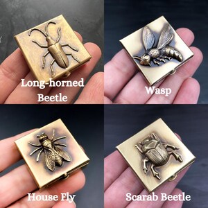 May include: Four small, square, brass boxes with different insect designs. The boxes are labeled "Long-horned Beetle", "Wasp", "House Fly", and "Scarab Beetle".
