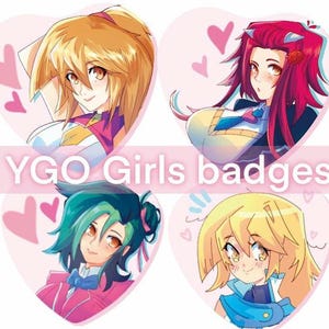 May include: Four heart-shaped badges featuring anime-style portraits of girls. Each badge has a different character with varying hair colors, including blonde, red, and teal. The text "YGO Girls badges" is displayed across the image.
