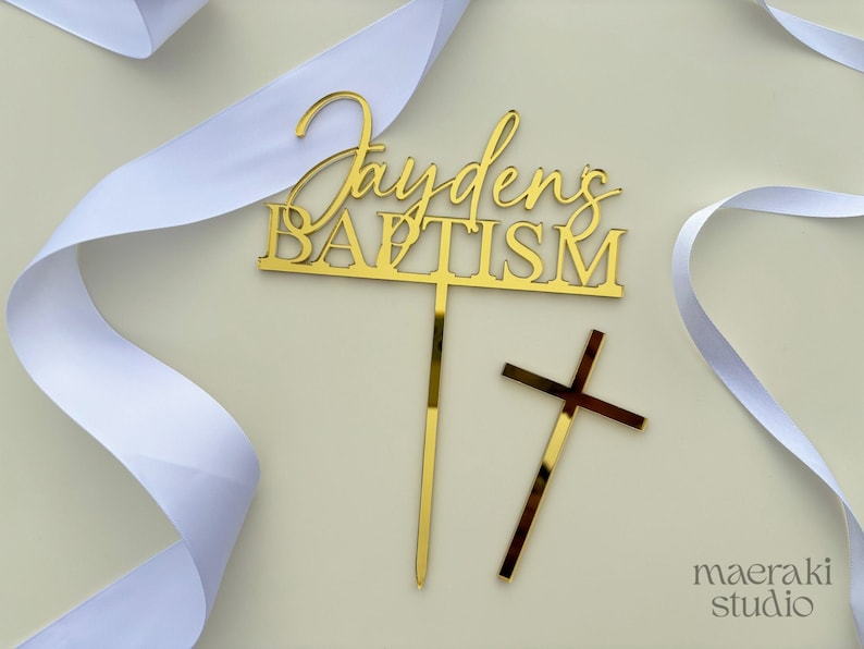 May include: Gold mirror acrylic cake topper with the text "Jayden's Baptism" and a separate gold cross.